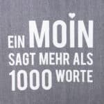 Inspirierendes Zitat auf grauem Stoff: "Ein Moin sagt mehr als 1000 Worte".