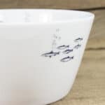 Ein weißer Porzellanbecher mit Fischmotiven, ideal für Fischliebhaber und hochwertige Geschirrsets.