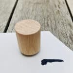 Holzklotz auf weißem Papier mit schwarzer Linie, auf Holztisch.
