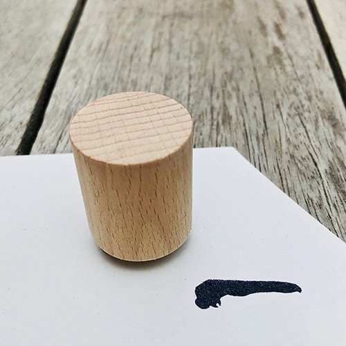 Holzklotz auf weißem Papier mit schwarzer Linie, auf Holztisch.