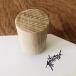 Hölzerner Korken auf weißem Papier mit Lavendelzeichnung, natürliche Materialqualität sichtbar.