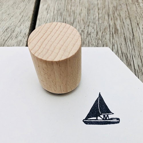 Hölzerner Holzstempel auf weißem Papier mit Segelboot-Design, für kreative Bastelarbeiten.