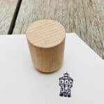 Holzstempel auf Papier mit Turmzeichnung, handgefertigtes Werkzeug für kreative Drucke.