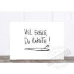 Viel Erfolg, du Rakete! Motivationsspruch auf weißer Wand mit Raketenzeichnung.