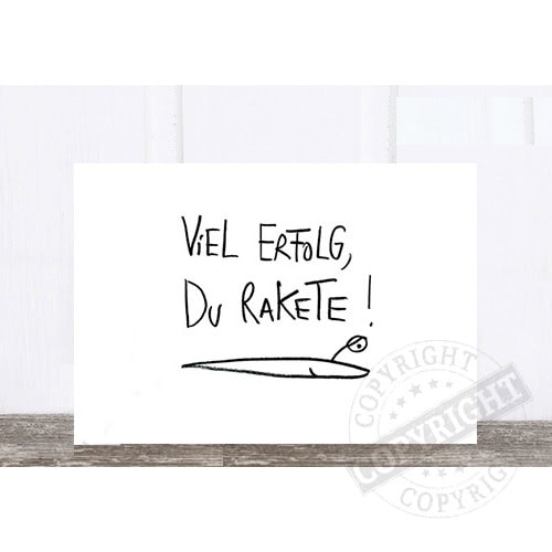 Viel Erfolg, du Rakete! Motivationsspruch auf weißer Wand mit Raketenzeichnung.