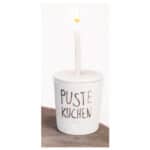 Ein Kerzenlicht in einem weißen Topf mit der Aufschrift "Puste Kuchen".