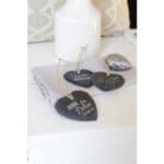 Hochwertige Steine mit Glückssprüchen als Dekoration auf weißem Tuch und Vase.