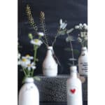 Blumen in weißen Flaschen, minimalistische Dekoration, natürliche Ästhetik, Fokus auf Pflanzen und k.