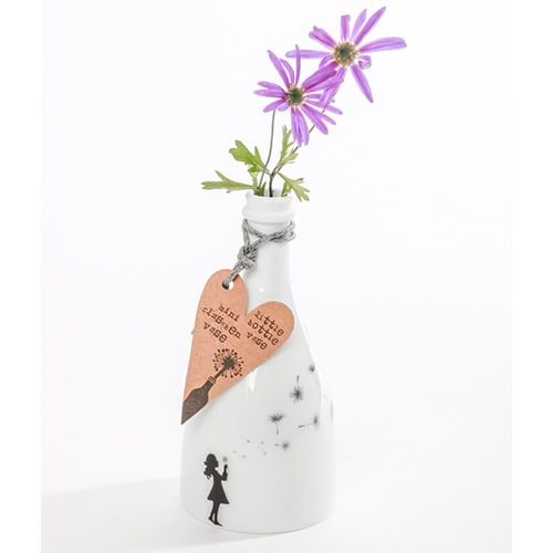 Blumen in weißer Vase mit Herzanhänger und Kindermotiv, dekoratives Blumenarrangement.