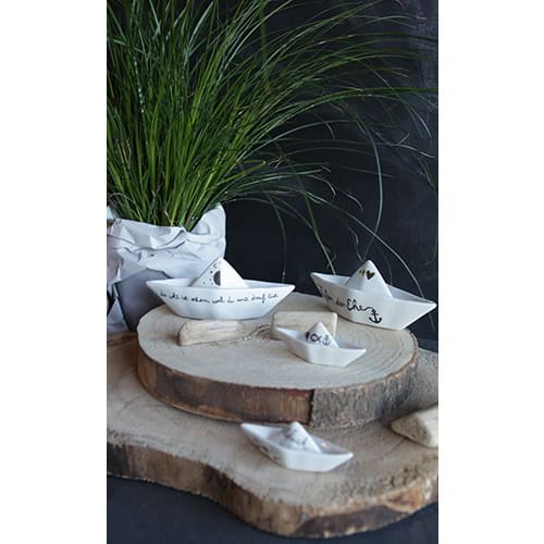 Hochwertige maritime Dekoration mit weißen Schiffsschalen auf Holzscheibe, grünem Gras und dunklem H.