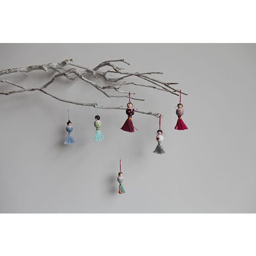 Handgefertigte Weihnachtsbaumschmuck-Anhänger aus Stoff und Holz, dekorativ an Zweig befestigt.