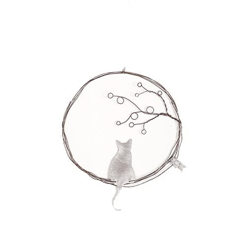 Katze vor einem runden Fenster mit Zweigen und Kugeln, stilvolle Tierfotografie.