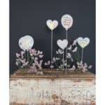 Bunte Herz- und Ballon-Dekoration mit Blumen auf Holzplatte, ideal für Feierlichkeiten und romantisc.