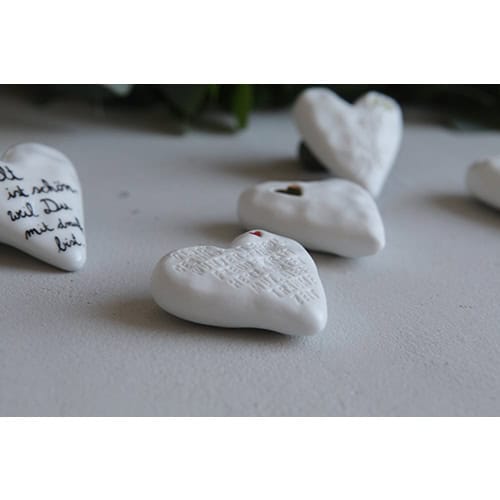 Herzförmige Steine mit eingravierten Botschaften und einem kleinen Loch, symbolisieren Liebe und Eri.