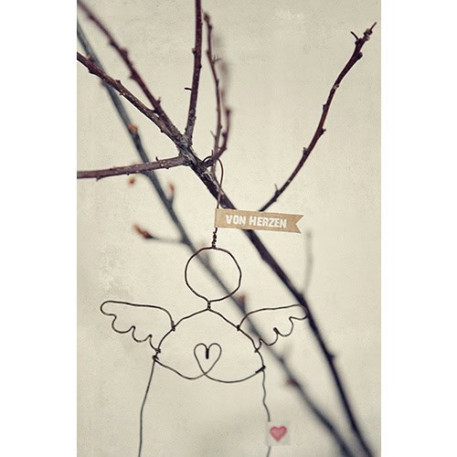 Herzanhänger aus Draht mit Engelsflügeln und Herz, hängend an Baumzweig, symbolisiert Liebe und Zune.