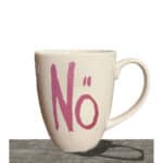 Kein Kaffee, keine Energie – weiße Tasse mit pinkem "No" Schriftzug auf Holzuntergrund.