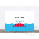 BLAUES WASSER MIT ZWEI ROTEN FISCHEN, DIE SICH UMARMEN, MIT DEM TEXT "Wale Liebe".