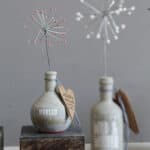 Dekorative Flasche mit Zierblume und Wunschkarte, modernes Wohnaccessoire.
