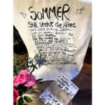 Sommergedicht auf Stoff mit Blumen und handgeschriebenem Text, sommerliche Stimmung.