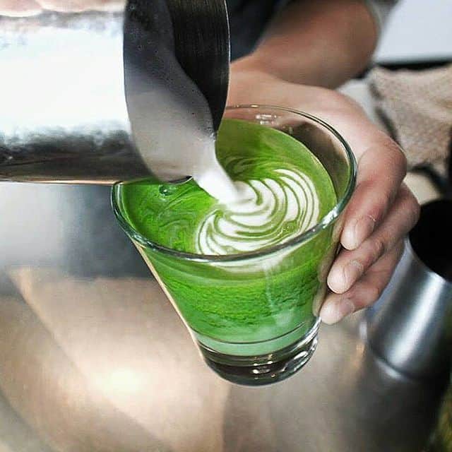 Frischer grüner Matcha Latte wird in einem Glas serviert, perfekt für Kaffee- und Teeliebhaber.