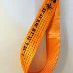 Hochwertiges orangefarbenes Sicherheits- oder Befestigungsgurt mit schwarzen Markierungen und Text,.