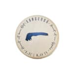 Ein Holzknopf mit blauer Lingeouc-Logo und handgeschriebenem Text, ideal für handgefertigte Kleidung.