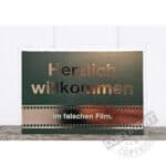 Herzlich willkommen im falschen Film - humorvoller Willkommensgruß auf Schultafel.