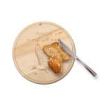 Ein Scheiben Brot auf einem runden Holzbrett mit Messer, mit dem Text "Hunger auf alles" und einer H.