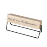 Der Holzstempel mit schwarzer Metallhalterung und inspirierendem Spruch.