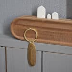 Schlüsselanhänger mit Gravur an Holzschrank, minimalistisches Design.