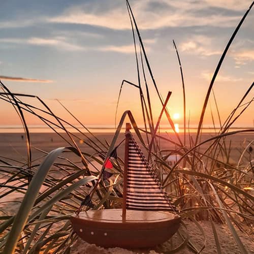 Hübsches Strandbild mit Boot und Sonnenuntergang am Meer, entspannte Urlaubsstimmung, Natur und Meer.