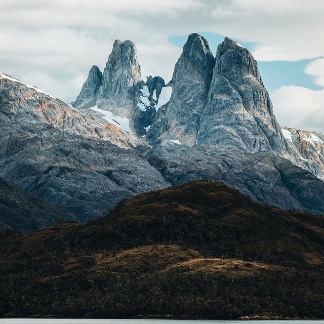 Majestätische Berggipfel in den Alpen mit schneebedeckten Spitzen und Wolken im Hintergrund.
