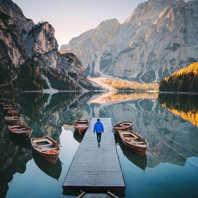 Bergsee mit Booten und Bergkulisse, ruhige Naturaufnahme.