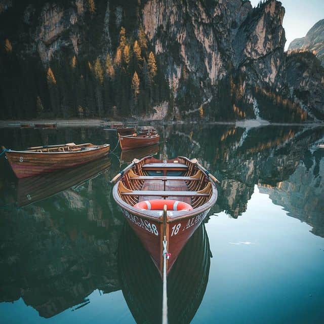 Boot auf ruhigem Bergsee mit Felswänden im Hintergrund.