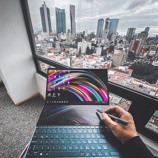 Hochauflösender Laptop mit Stift vor Fenster mit Stadtpanorama.