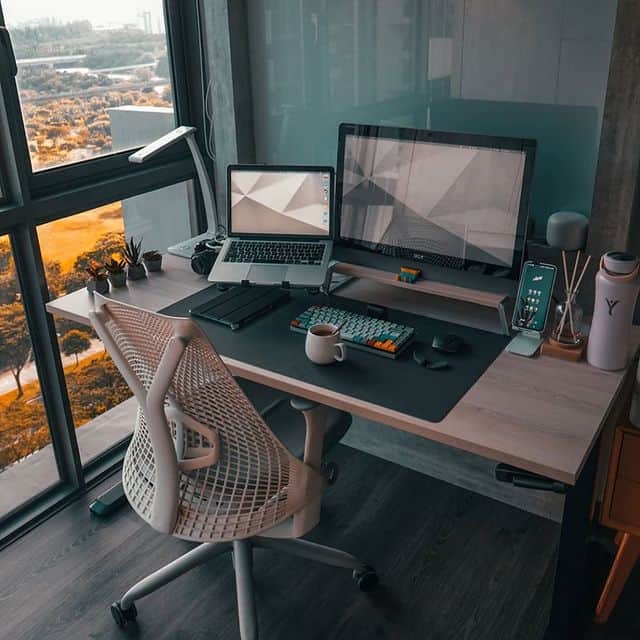 Moderner Arbeitsplatz mit Computer, Laptop und Blick auf die Stadt.