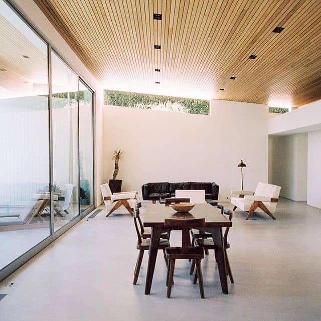 Heller, moderner Wohnraum mit Holzdecke, großen Fenstern und minimalistischer Einrichtung.