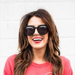 Modische Frau mit Sonnenbrille, lächelnd, im urbanen Look.