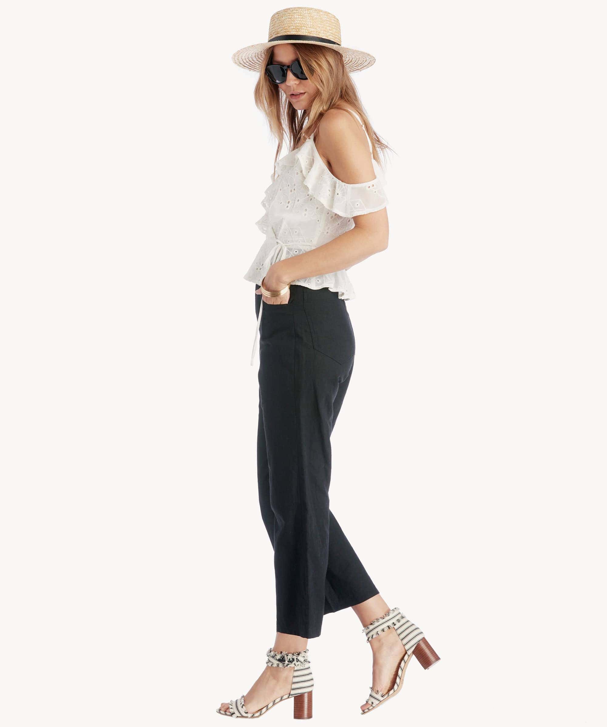Frau in Sommeroutfit mit Hut, Sonnenbrille und High Heels, modisch und elegant.