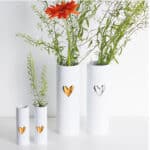 Elegante weiße Vasen mit Herzdekor und frischen Blumen, modernes Dekor für Zuhause oder Büro.