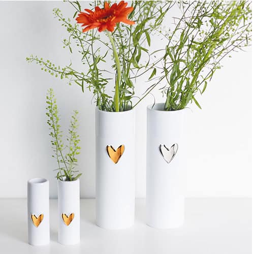 Elegante weiße Vasen mit Herzdekor und frischen Blumen, modernes Dekor für Zuhause oder Büro.