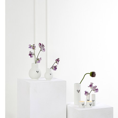 Blumenvasen mit Lavendel und Gänseblümchen auf weißen Podesten, minimalistische Dekoration.