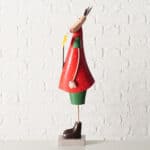 Ein dekorativer Weihnachtsengel aus Holz mit rotem Kleid, grüner Basis und goldener Stern, steht vor.