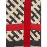 Hochwertiges Stoffmuster mit rotem Kreuz und schwarzem Monogramm-Design, stilvoll und elegant.