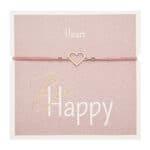 Herzarmband mit "Be Happy" Schriftzug auf rosa Hintergrund.